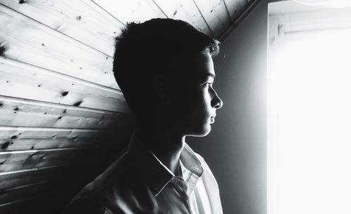 Portrait of young man looking away against wall