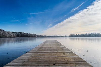 Pier over lake against blue sky