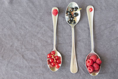 Red and black currant and loganberries on the iron spoon on the gray background. large group 