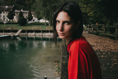 Portrait of young woman standing by water