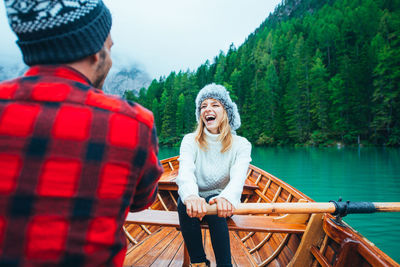 Man and woman looking at lake against trees