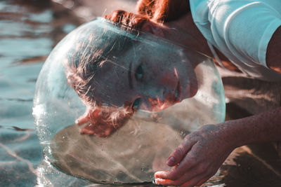 Close-up of woman wearing glass container at lake