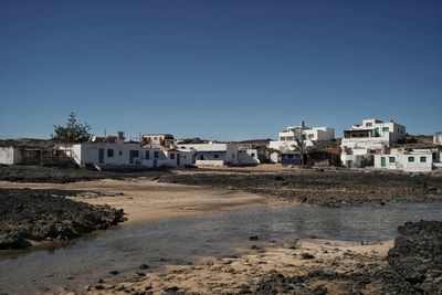 Buildings by beach against clear blue sky