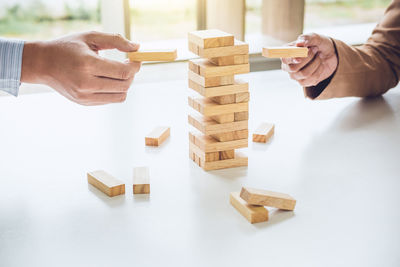 Cropped image of businessmen playing with toy blocks on table