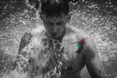 Portrait of shirtless man splashing water