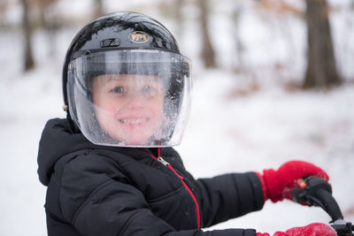 Portrait of boy wearing crash helmet while riding bicycle during winter