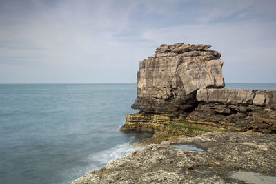 Rock formation on sea shore against sky