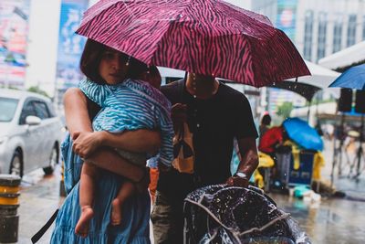 Rear view of man and woman in wet city during rainy season