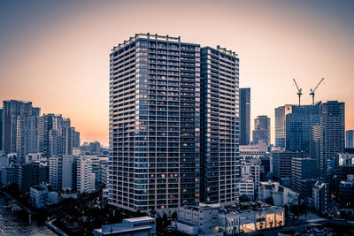 Modern buildings in city against sky during sunset