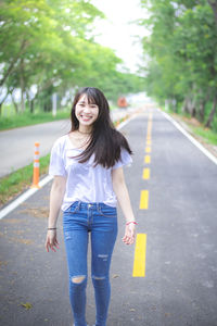 Portrait of smiling young woman standing on road