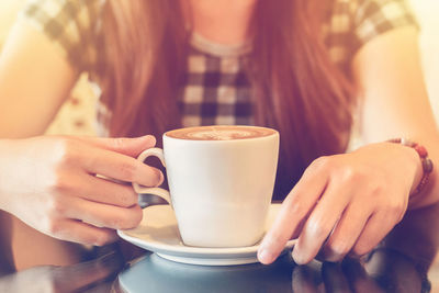 Midsection of woman holding coffee cup