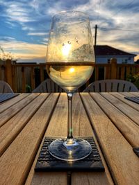 Close-up of wineglass on table against sky during sunset