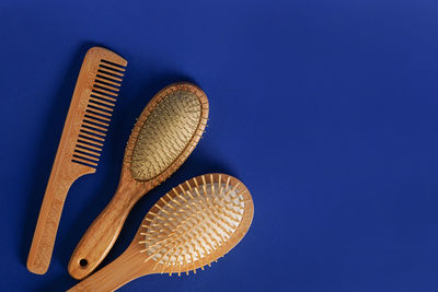 Wooden hair combs on blue background with copy space