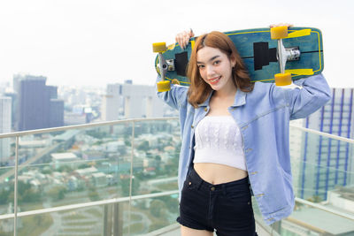 Portrait of smiling young woman standing against railing