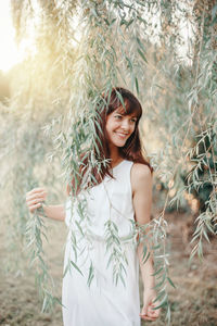 Smiling woman standing by tree