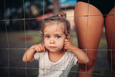 Portrait of cute girl standing by fence