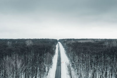 Empty road amidst field against sky