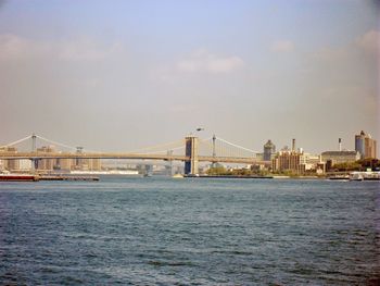 Bridge over sea by buildings in city against sky