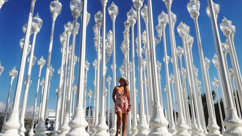 Low angle view of woman standing against blue sky