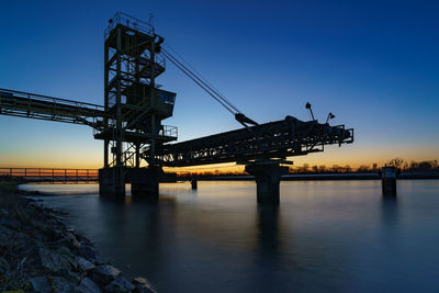 Bridge over river against sky during sunset