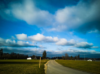 Street amidst field against sky