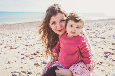 Portrait of happy woman sitting on shore at beach against sky