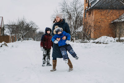 Outdoor family activities for happy winter holidays. happy mother and two sons playing snowballs on