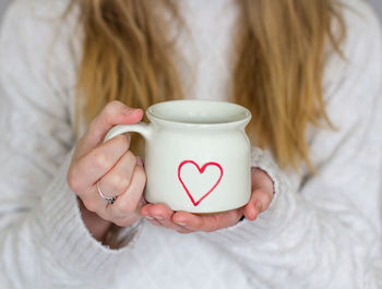 Midsection of woman holding cup