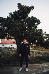 Full length of young man standing against tree