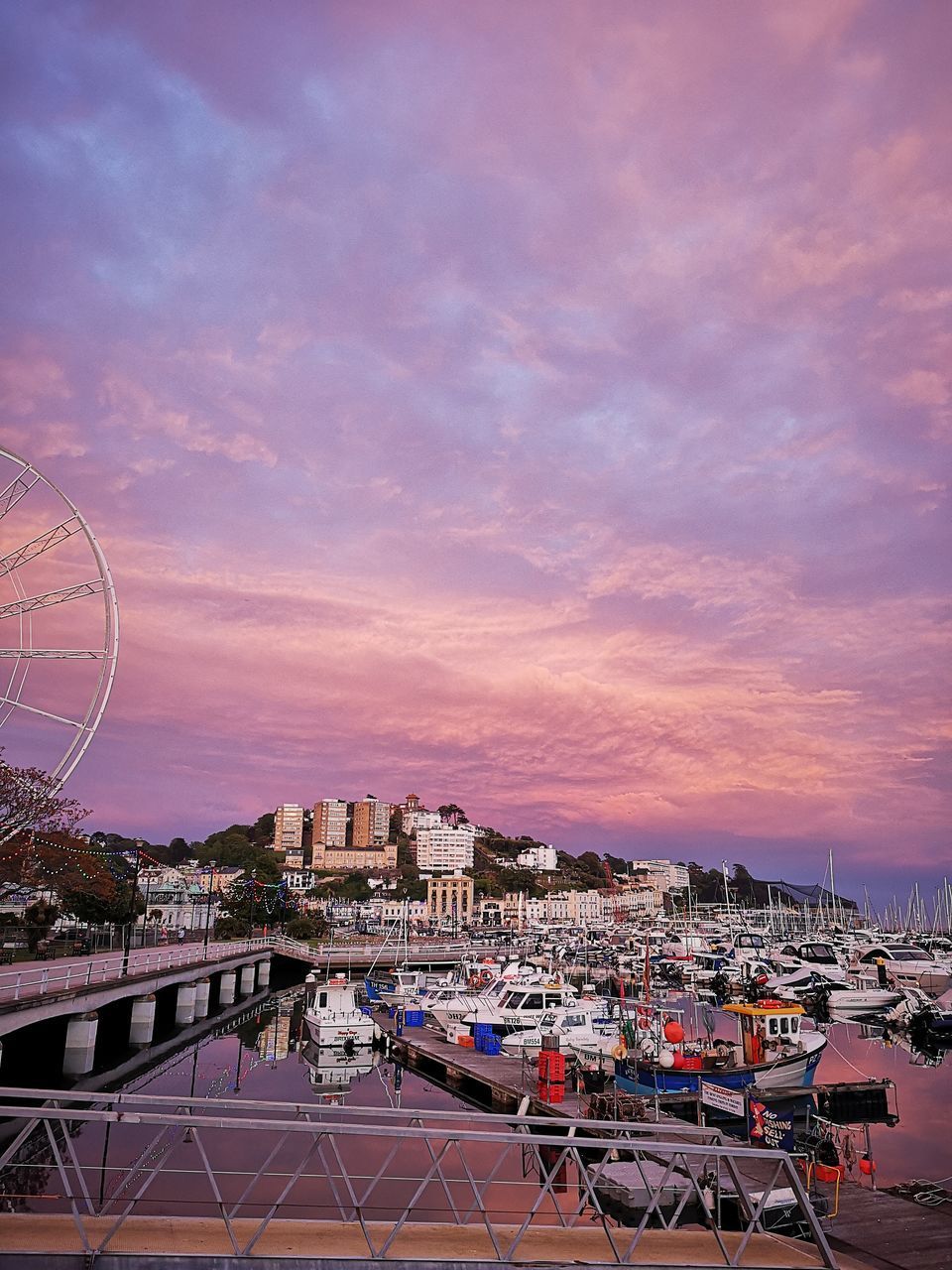 HIGH ANGLE VIEW OF FERRIS WHEEL BY BUILDINGS AGAINST SKY