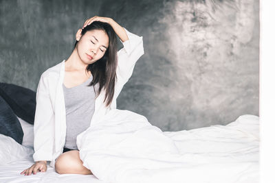 Young woman sitting on bed