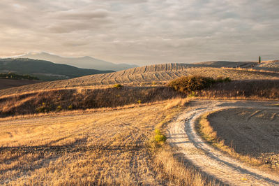 Scenic view of road by mountains against sky