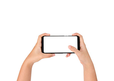 Close-up of hand holding mobile phone against white background