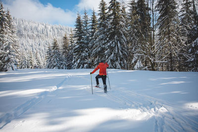 Rear view of man skiing on snow covered landscape