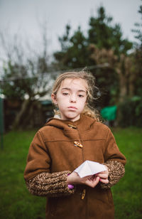 Portrait of girl holding origami while standing on land