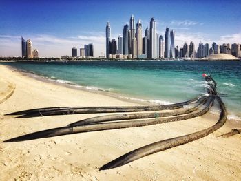 Black pipes on beach against cloudy sky