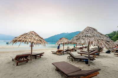 Panoramic view of lounge chairs on beach against clear sky