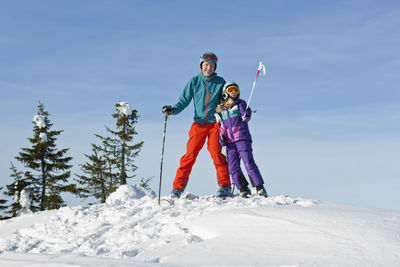 Father and daughter skiing, low angle view