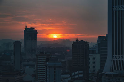 Buildings in city against romantic sky at sunset