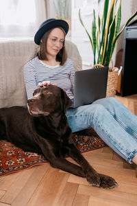 Woman with dog sitting on floor at home
