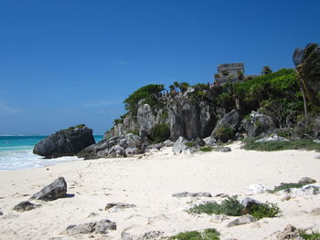 Rocks on beach against clear blue sky