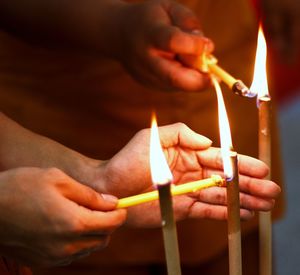 Close-up of hands holding candles