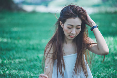 Young woman looking away while standing on field