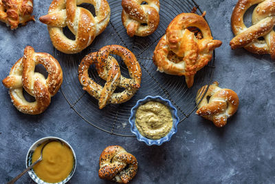 Top down view of homemade baked pretzels on a cooling rack with mustard dips.