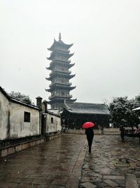 Rear view of man walking on footpath during rainy season