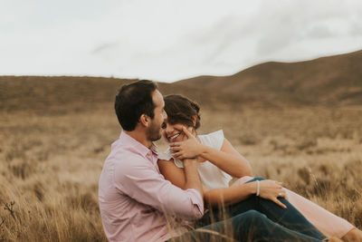 Young couple on field against sky