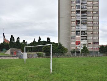 Built structure on field by buildings against sky