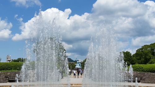 Fountain in public park against cloudy sky
