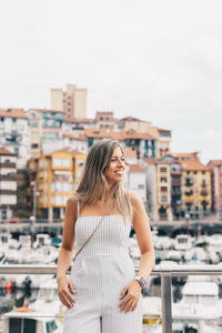 Young woman looking away while standing against cityscape