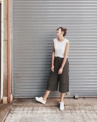 Happy woman looking away while standing against closed shutter